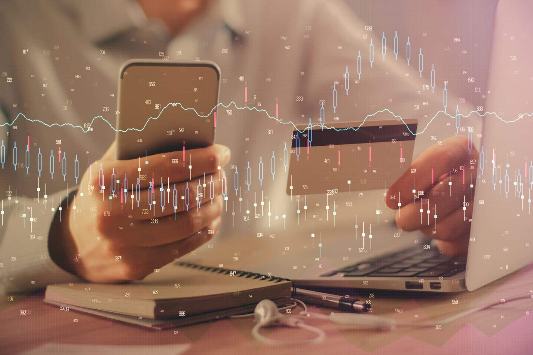 A crypto graph is superimposed over a photo of a person sitting at their desk holding their phone and a credit card.