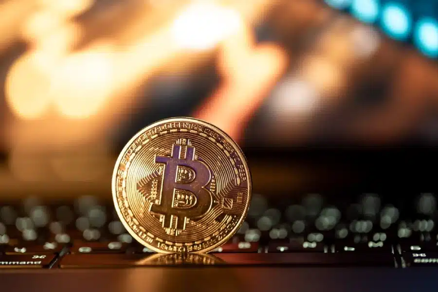 A gold bitcoin sitting on a keyboard.