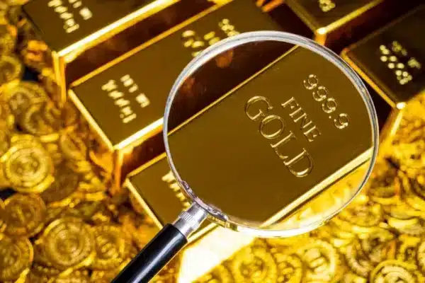 A magnifying glass looking at gold bars.