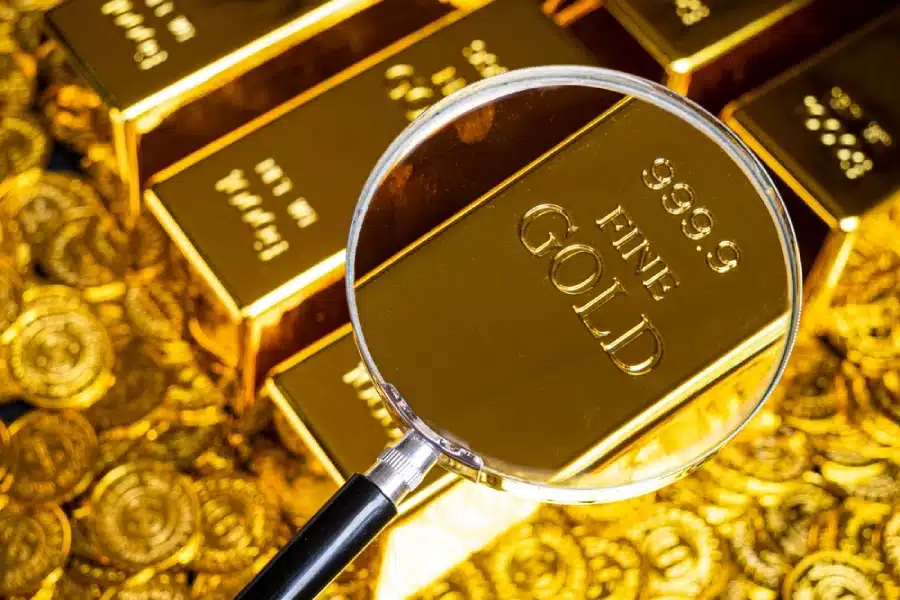 A magnifying glass looking at gold bars.